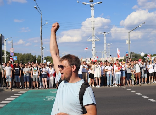 man in white and black crew neck t-shirt raising his right hand