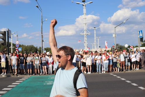 man in white and black crew neck t-shirt raising his right hand