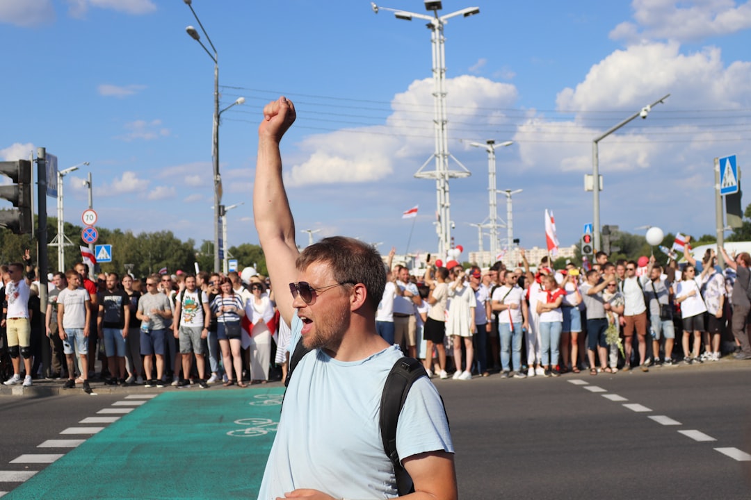 man in white and black crew neck t-shirt raising his right hand