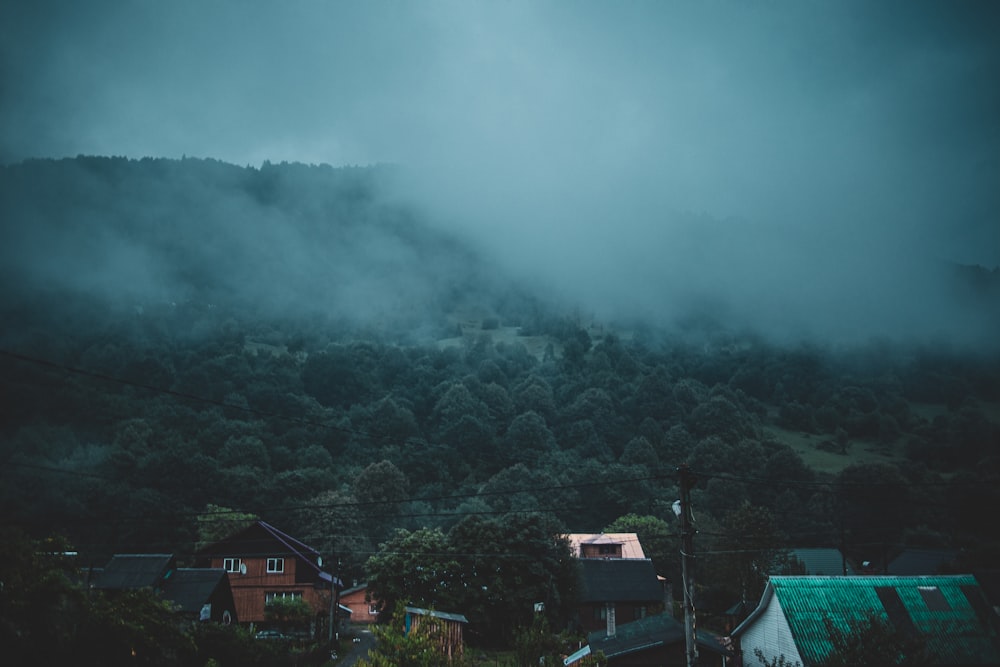 green and brown houses on green mountain under white clouds during daytime