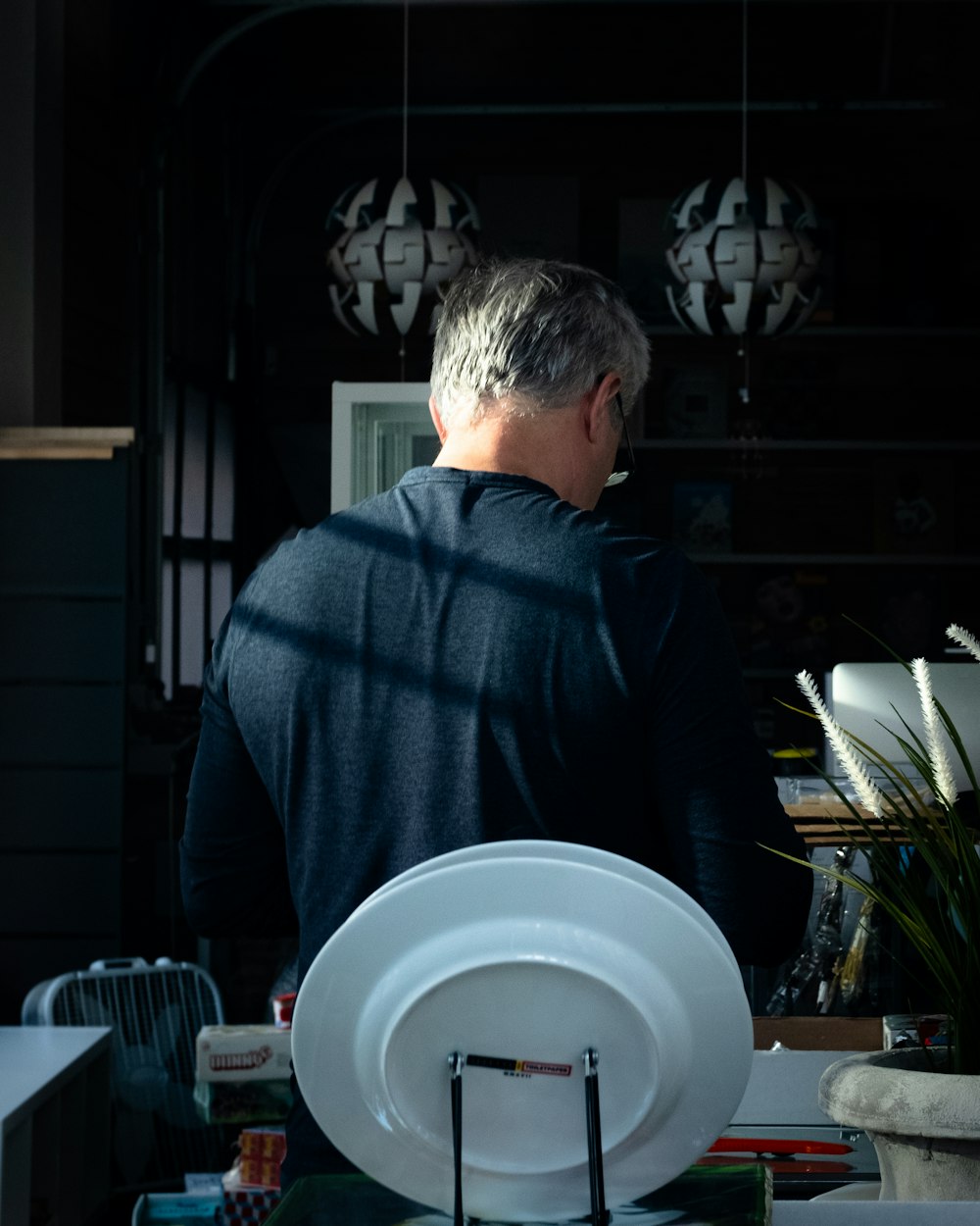 man in blue sweater holding white ceramic plate