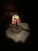 A repaired stained glass lamp casting colorful patterns on a wooden table.
