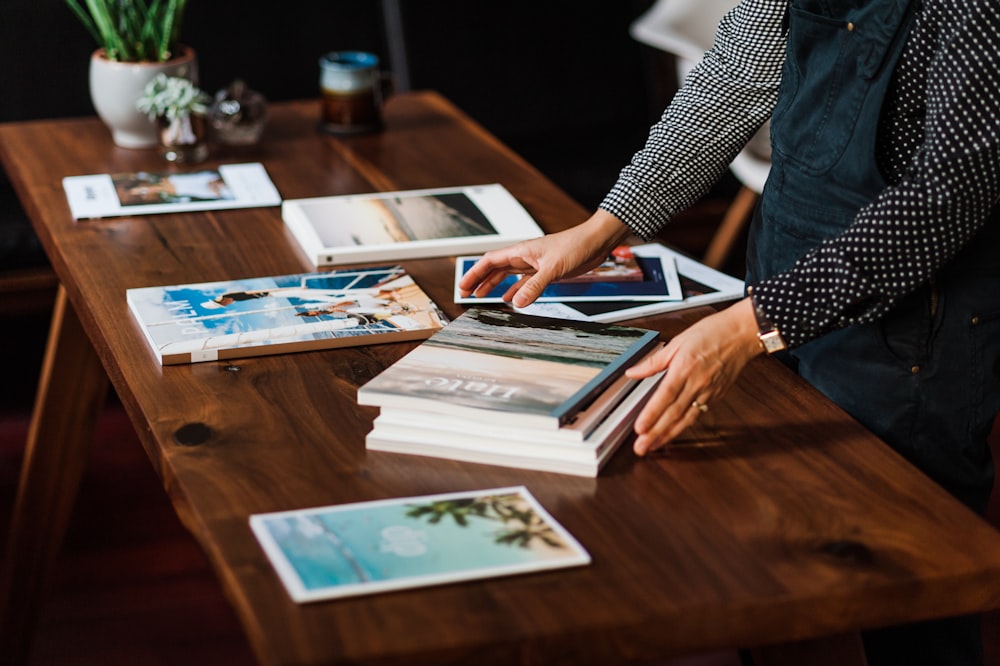 person in black and white long sleeve shirt holding white and blue book