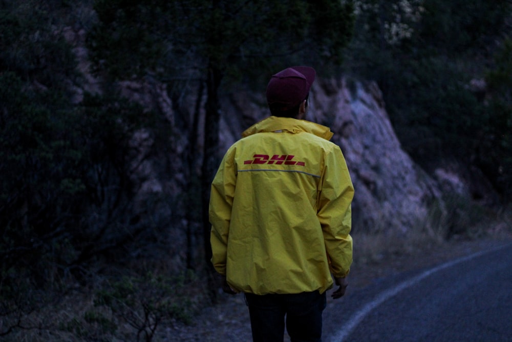 man in yellow jacket standing on road during daytime