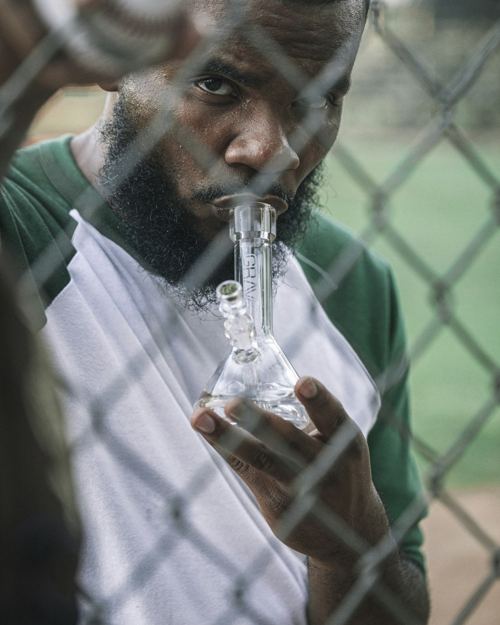 man in green crew neck t-shirt drinking water from clear glass bottle