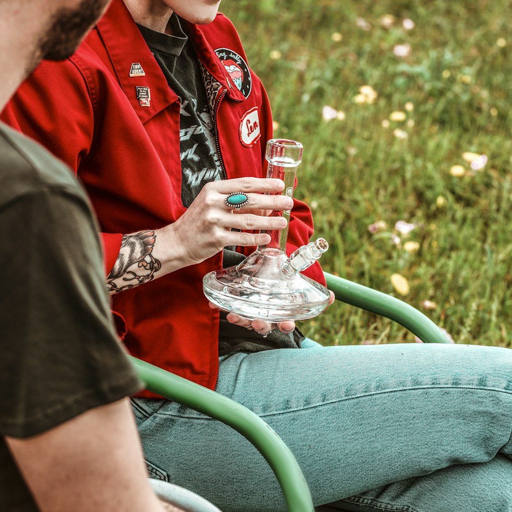 man in red button up shirt and blue denim jeans sitting on green metal armchair