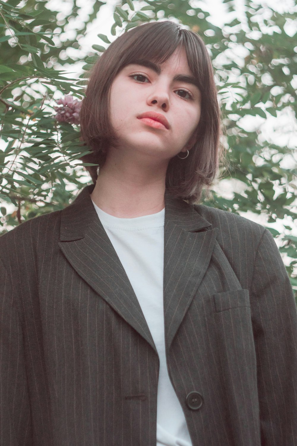 woman in gray blazer standing near pink flower tree during daytime