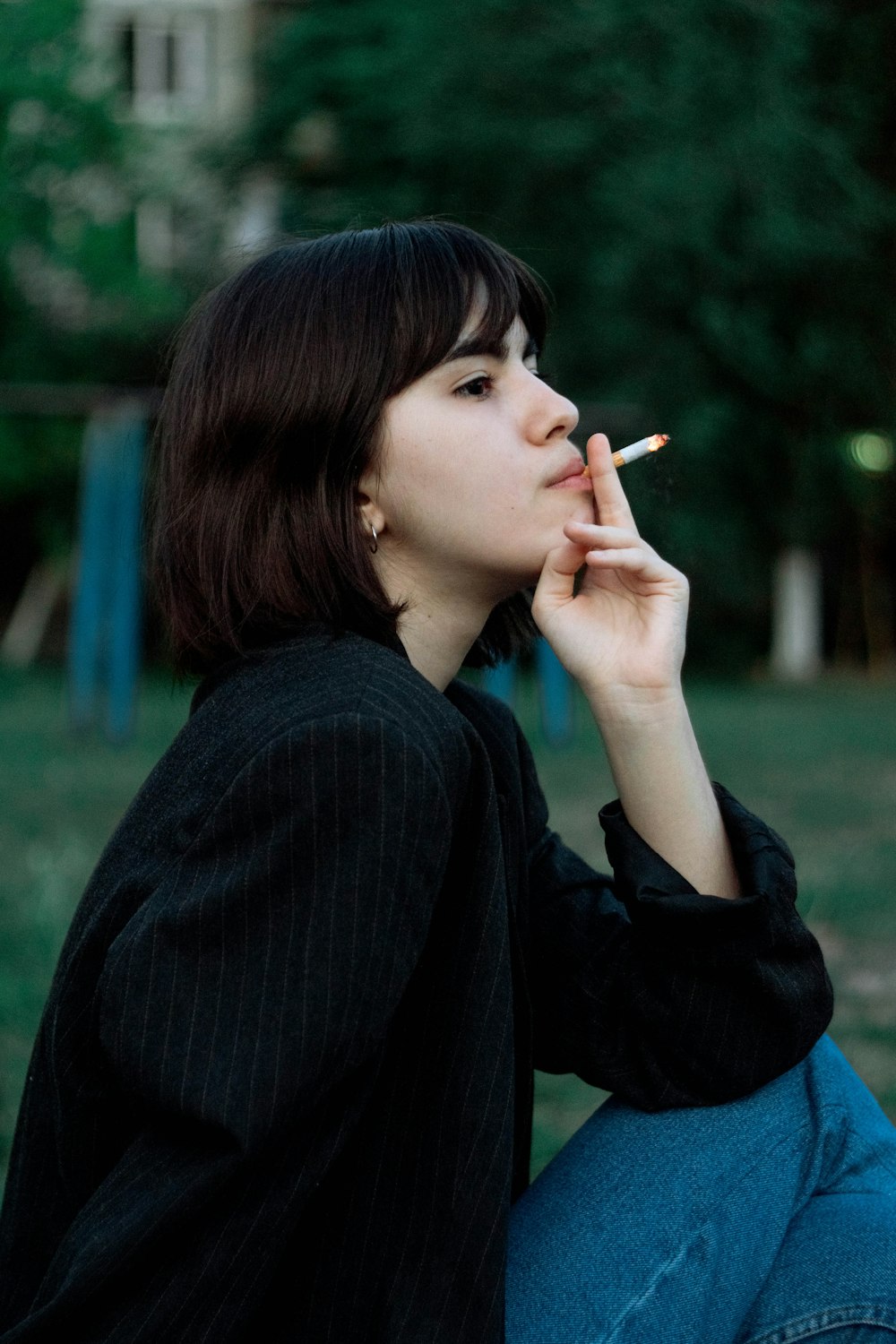 mulher na camisa preta de manga comprida que fuma o cigarro