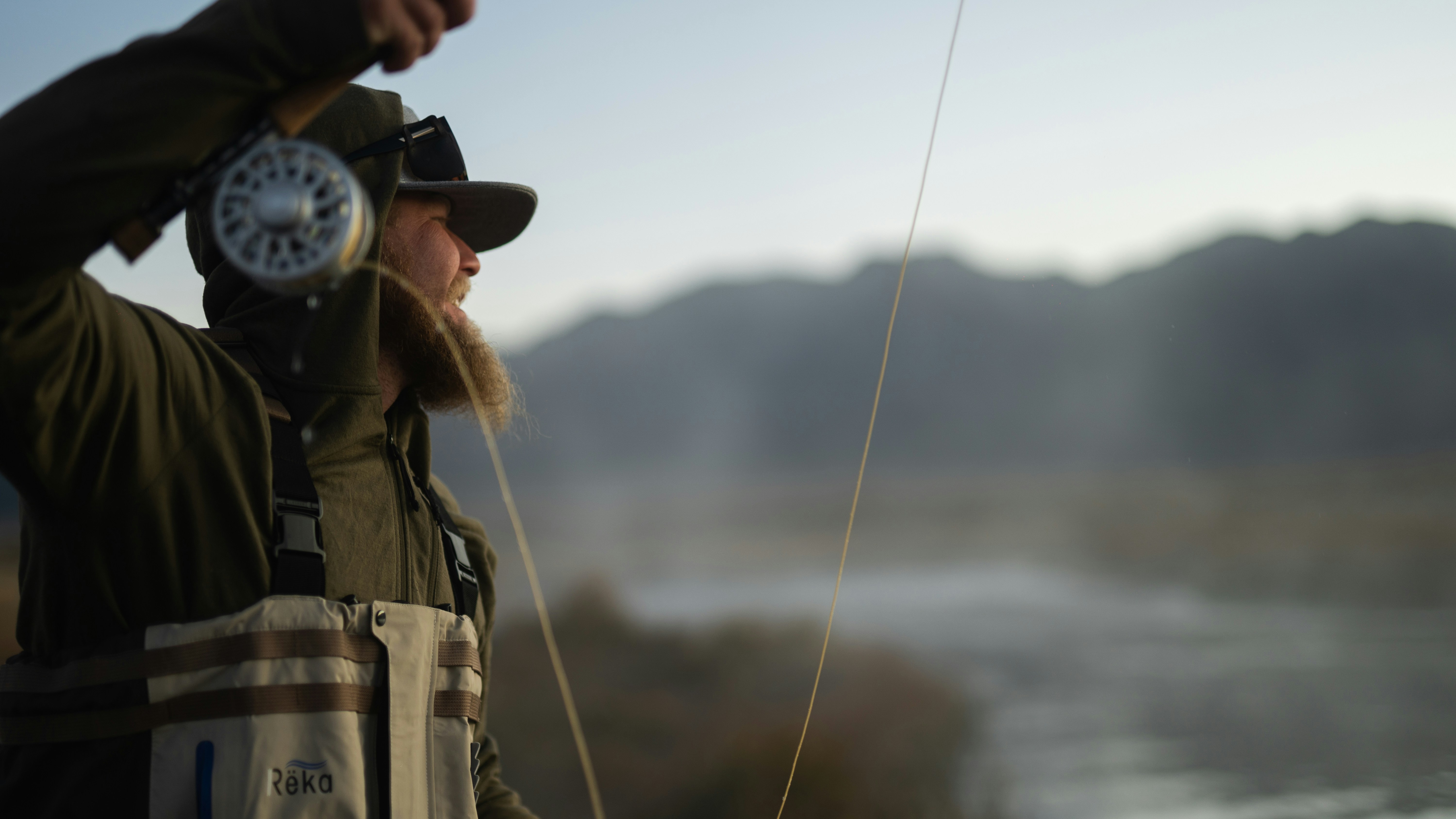 man in brown jacket and white helmet holding fishing rod
