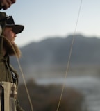 man in brown jacket and white helmet holding fishing rod