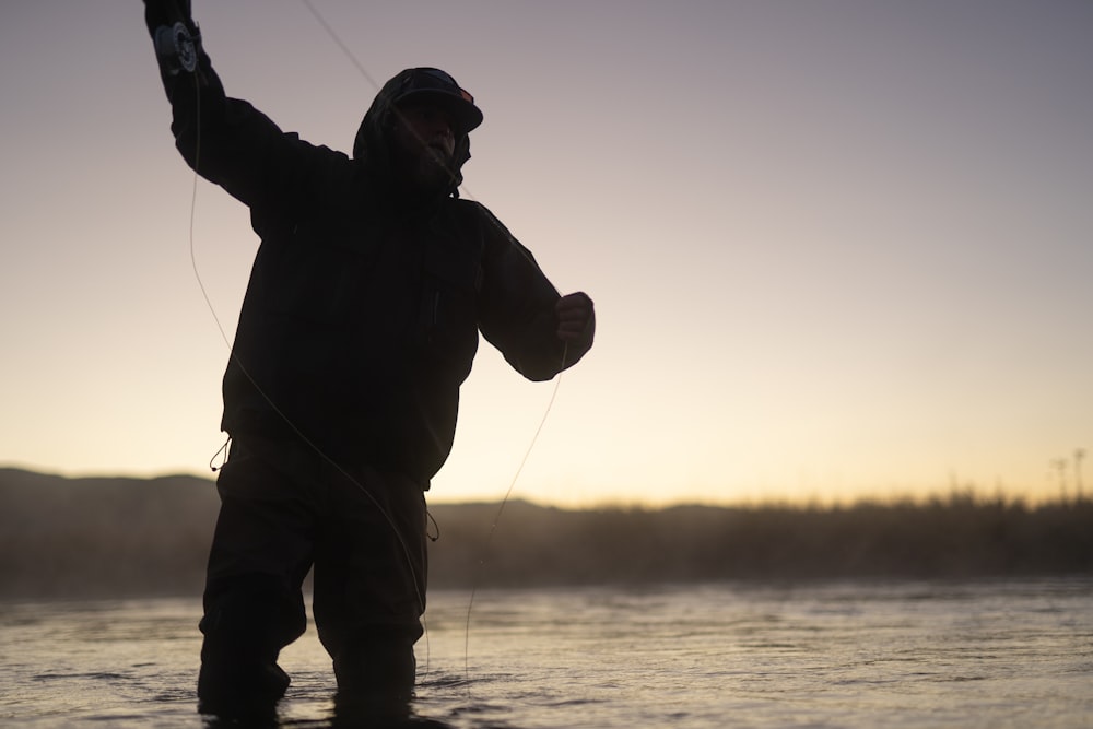 man in black jacket and brown pants fishing during daytime