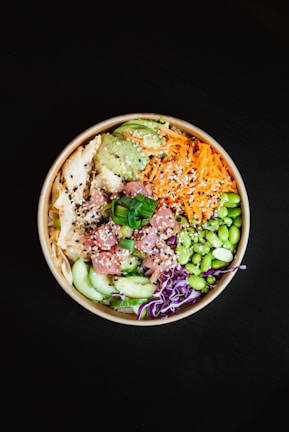 Colorful pokebowl with rice, fresh fish, avocado, and a sprinkle of sesame seeds.