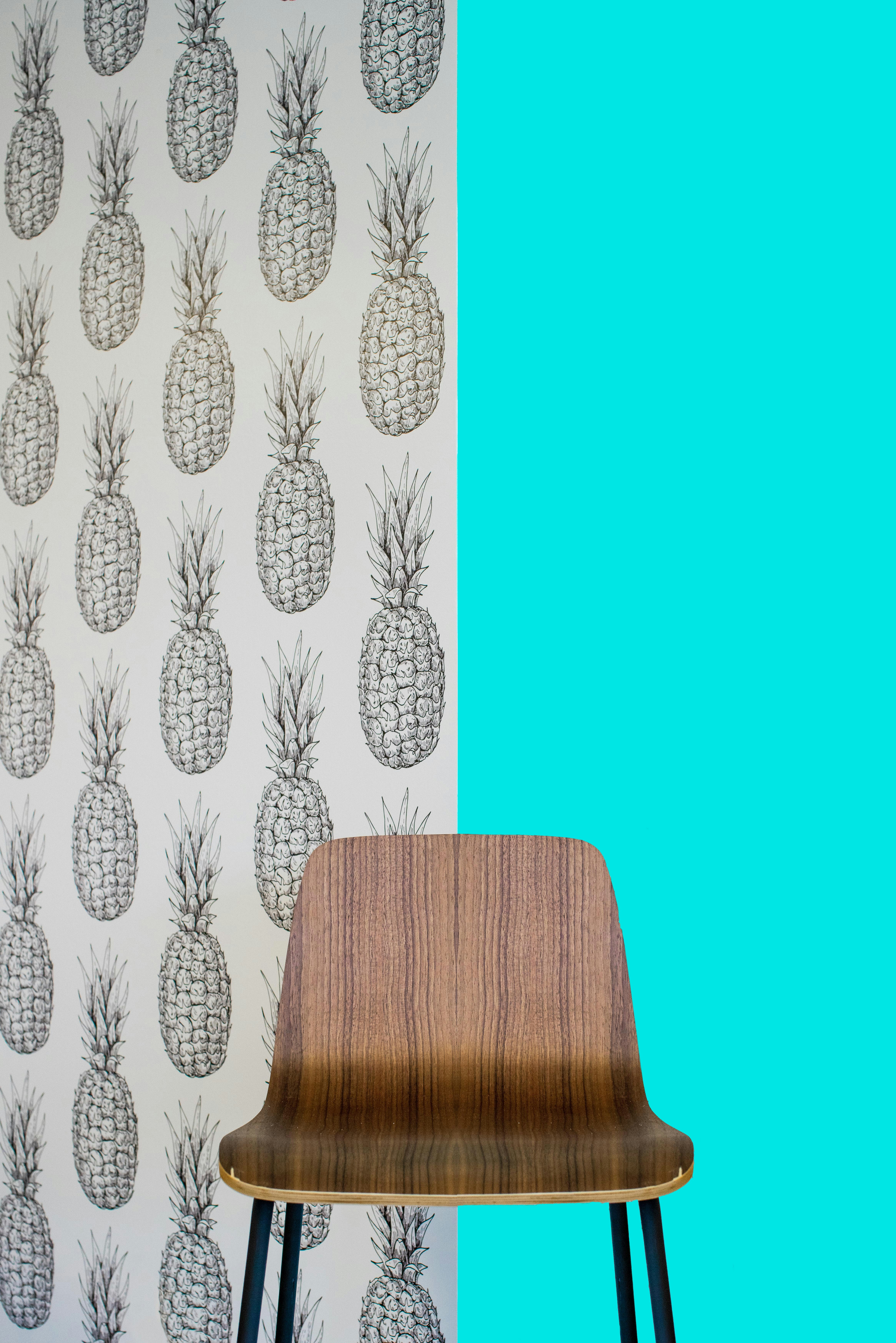 Siège en bois marron à côté d’un mur floral blanc et bleu