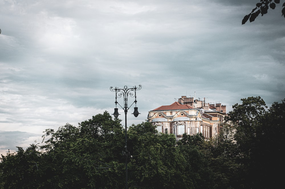 white and brown concrete building near green trees under white clouds during daytime