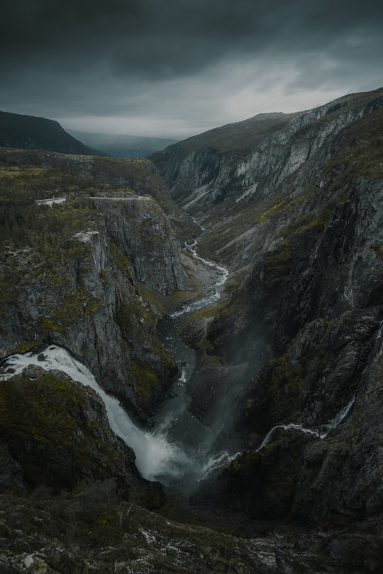 green and brown mountain under white clouds during daytime in Vøringfossen Norway