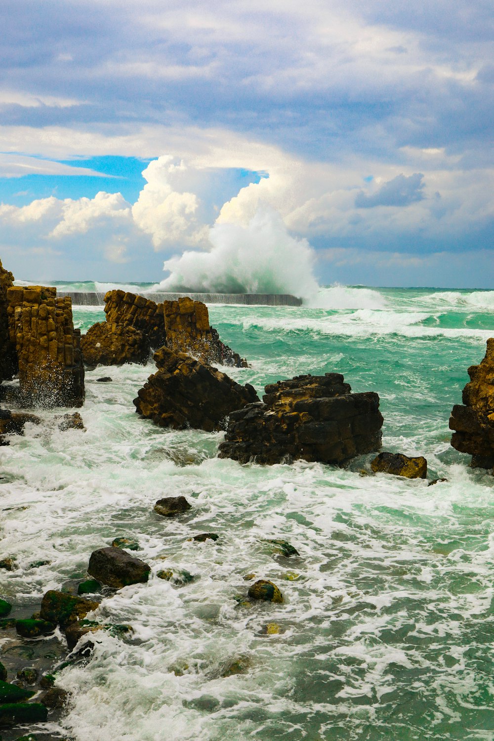 brown rock formation on sea under blue sky during daytime