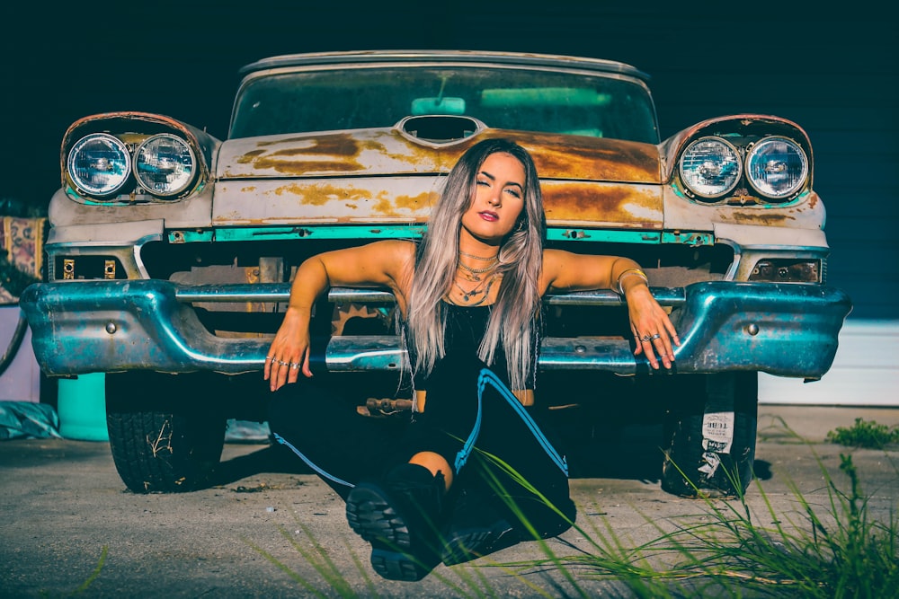 woman in black leather jacket and black pants sitting on black car