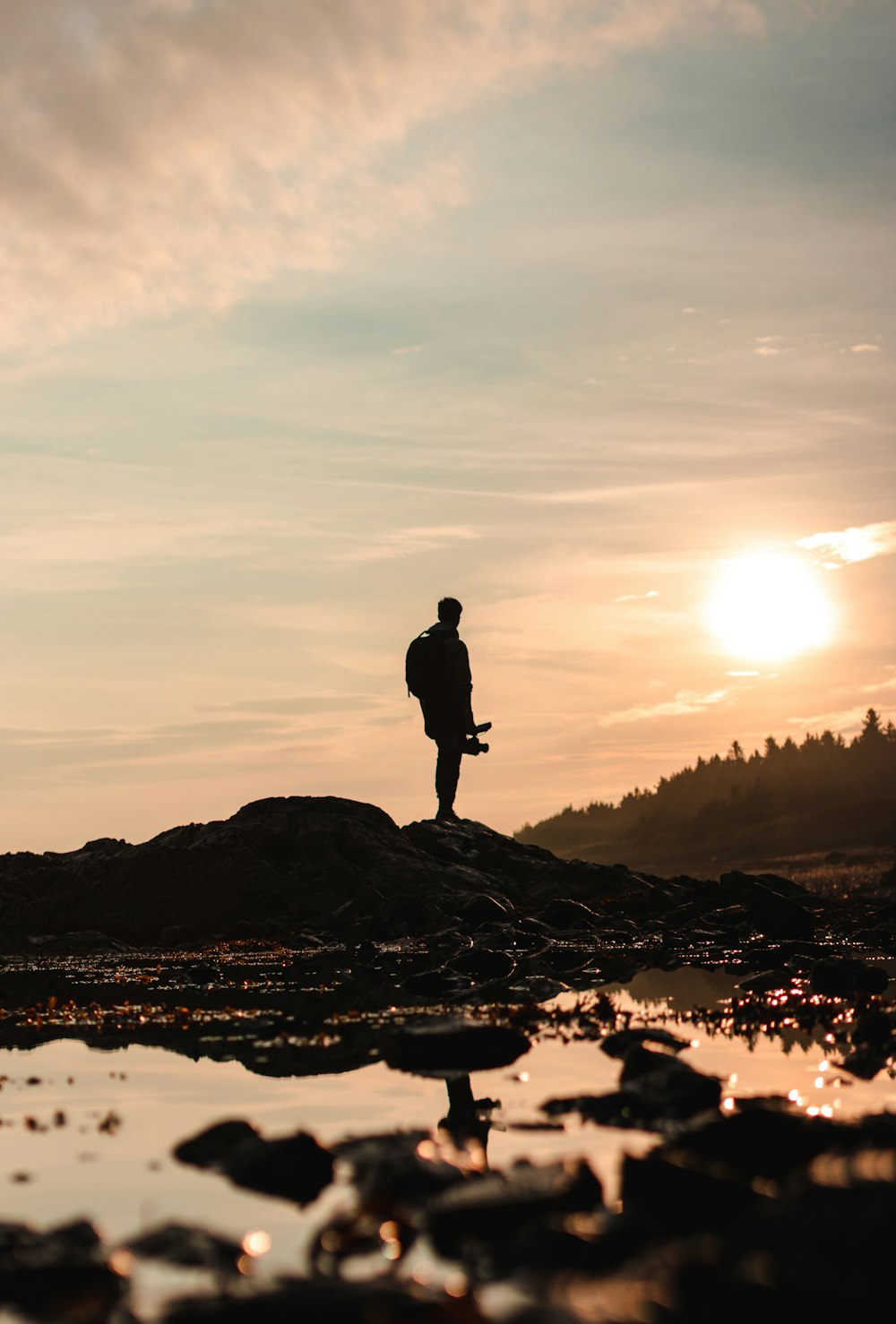 silhouette of man standing on rock formation during sunset