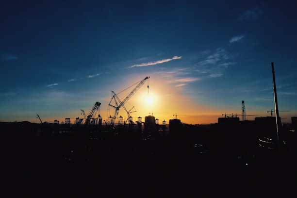 Modern construction site with cranes and scaffolding during sunset.