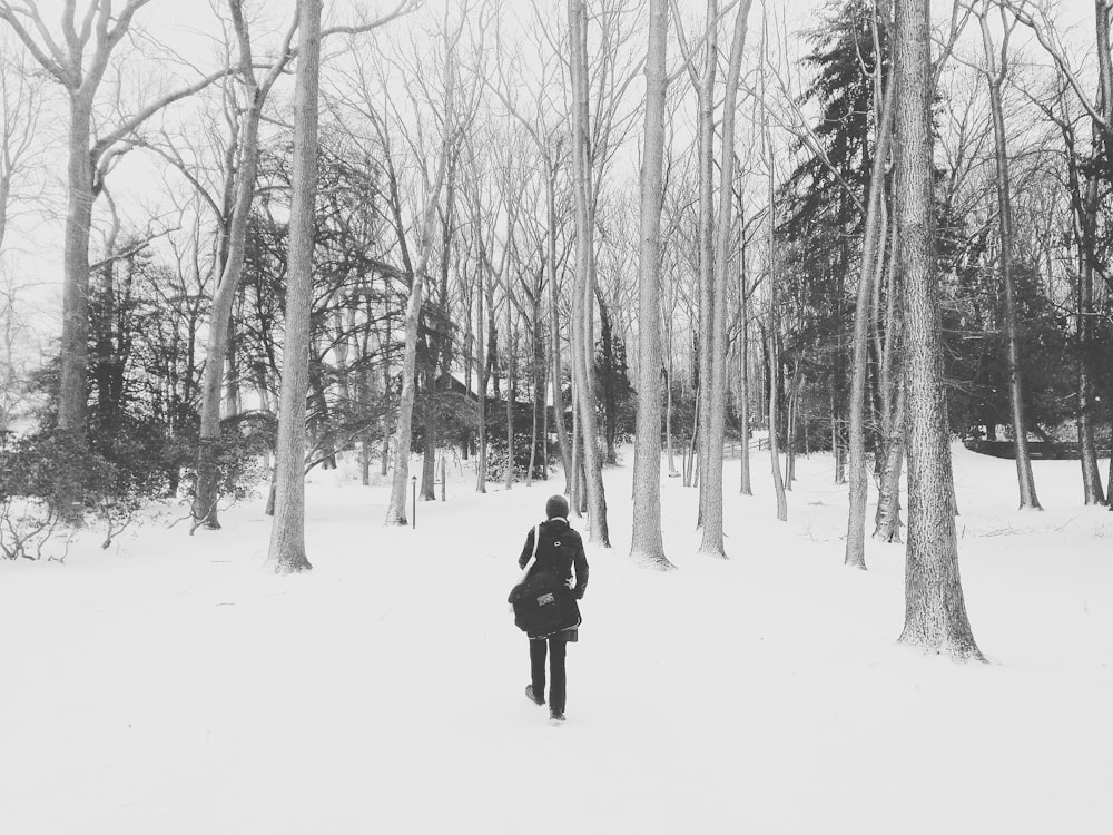 person in black coat walking on snow covered ground