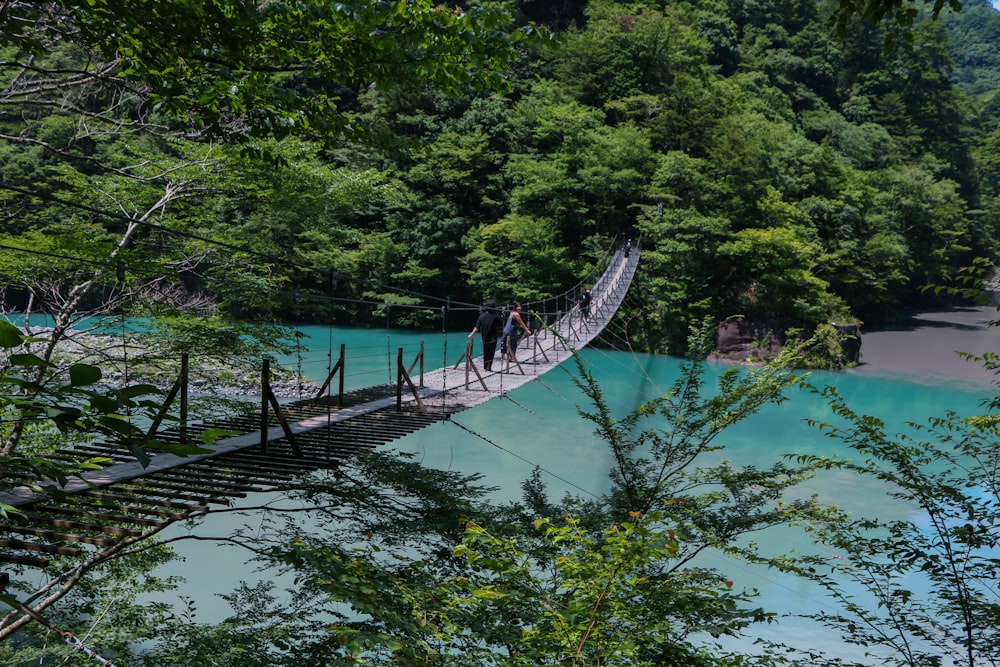 two people crossing a bridge over a river