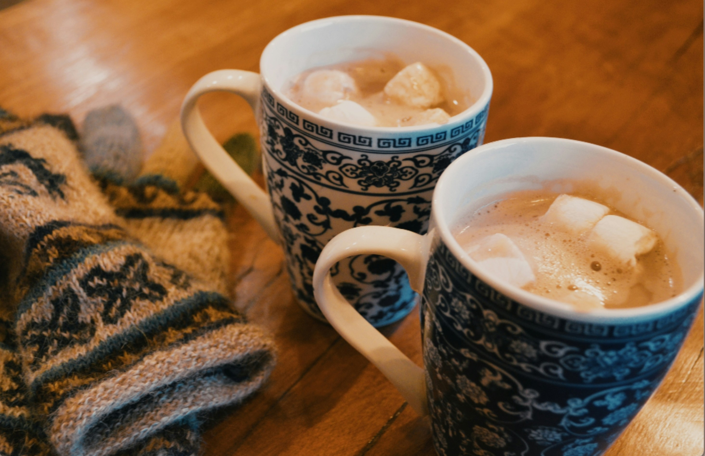 Close-up of two warm tea mugs sitting untouched on a rustic wooden table