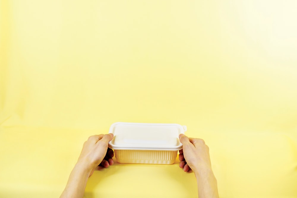 person holding white plastic container