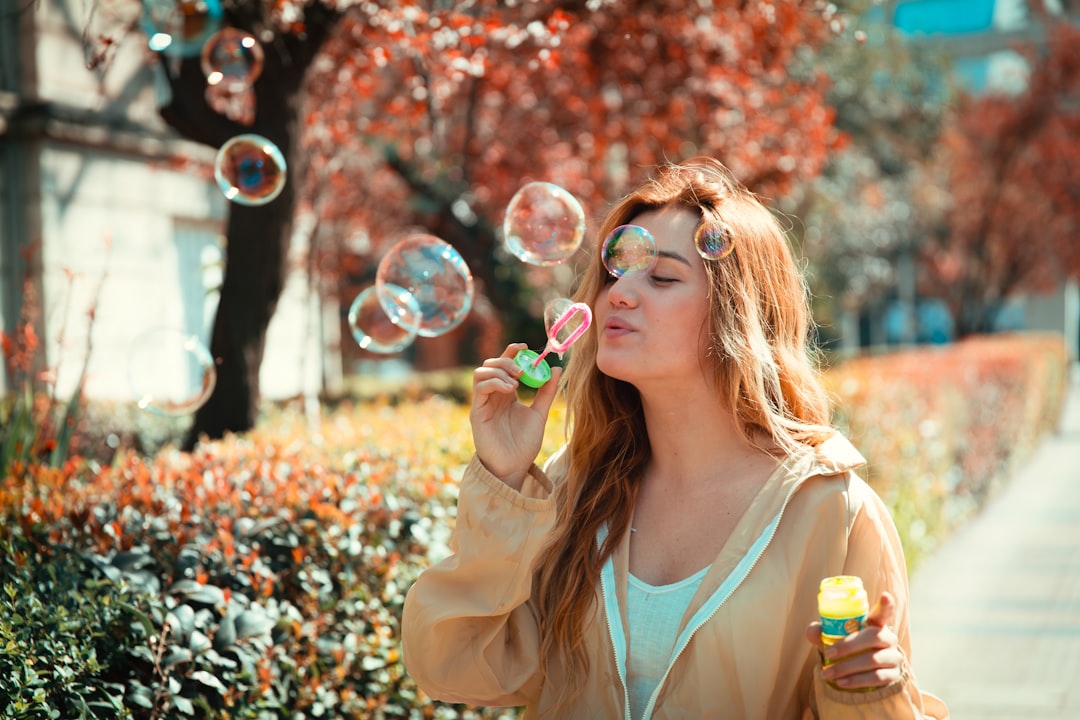 woman in white tank top blowing bubbles