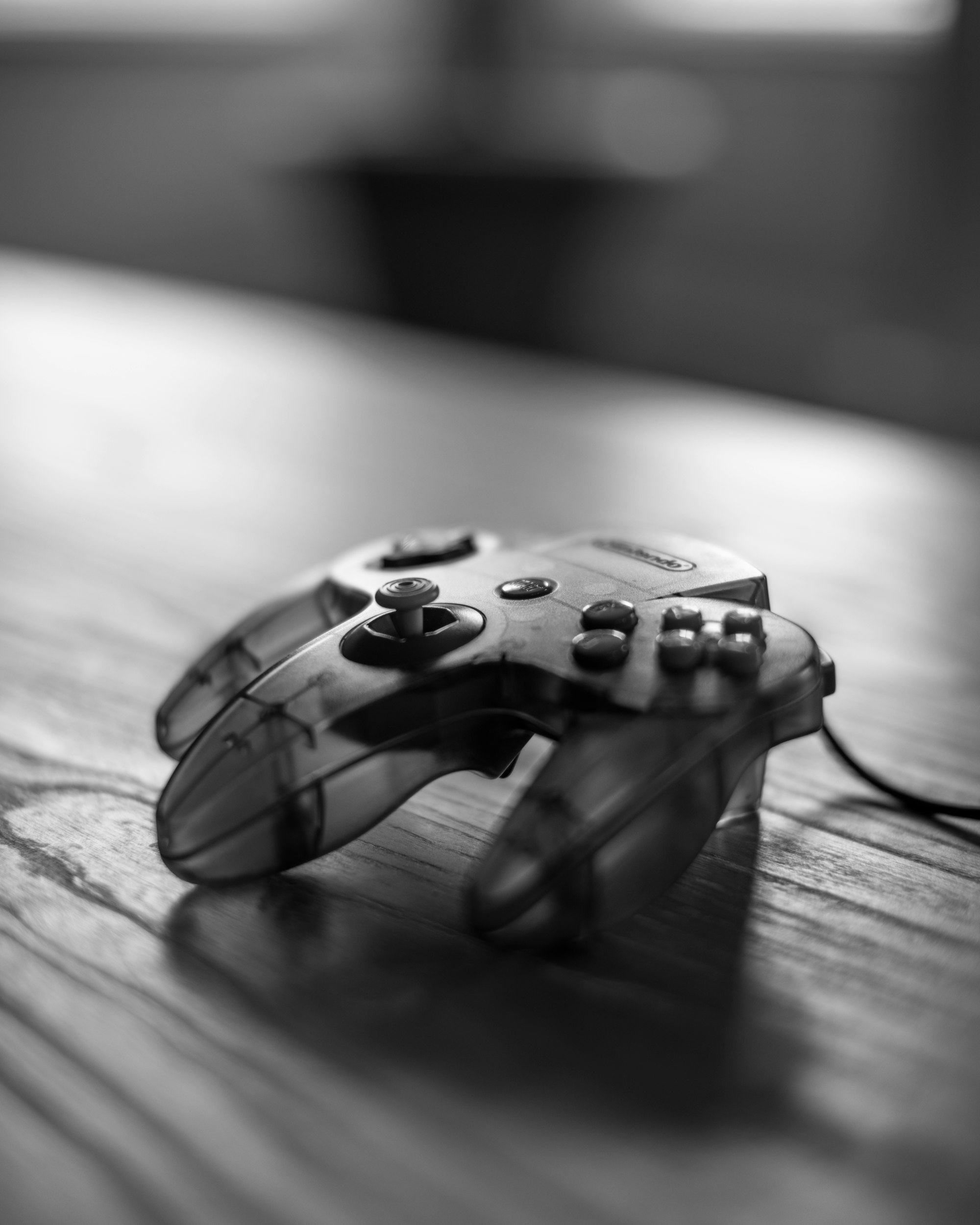 A closeup of a three-pronged, see-through Nintendo 64 controller, in black-and-white.
