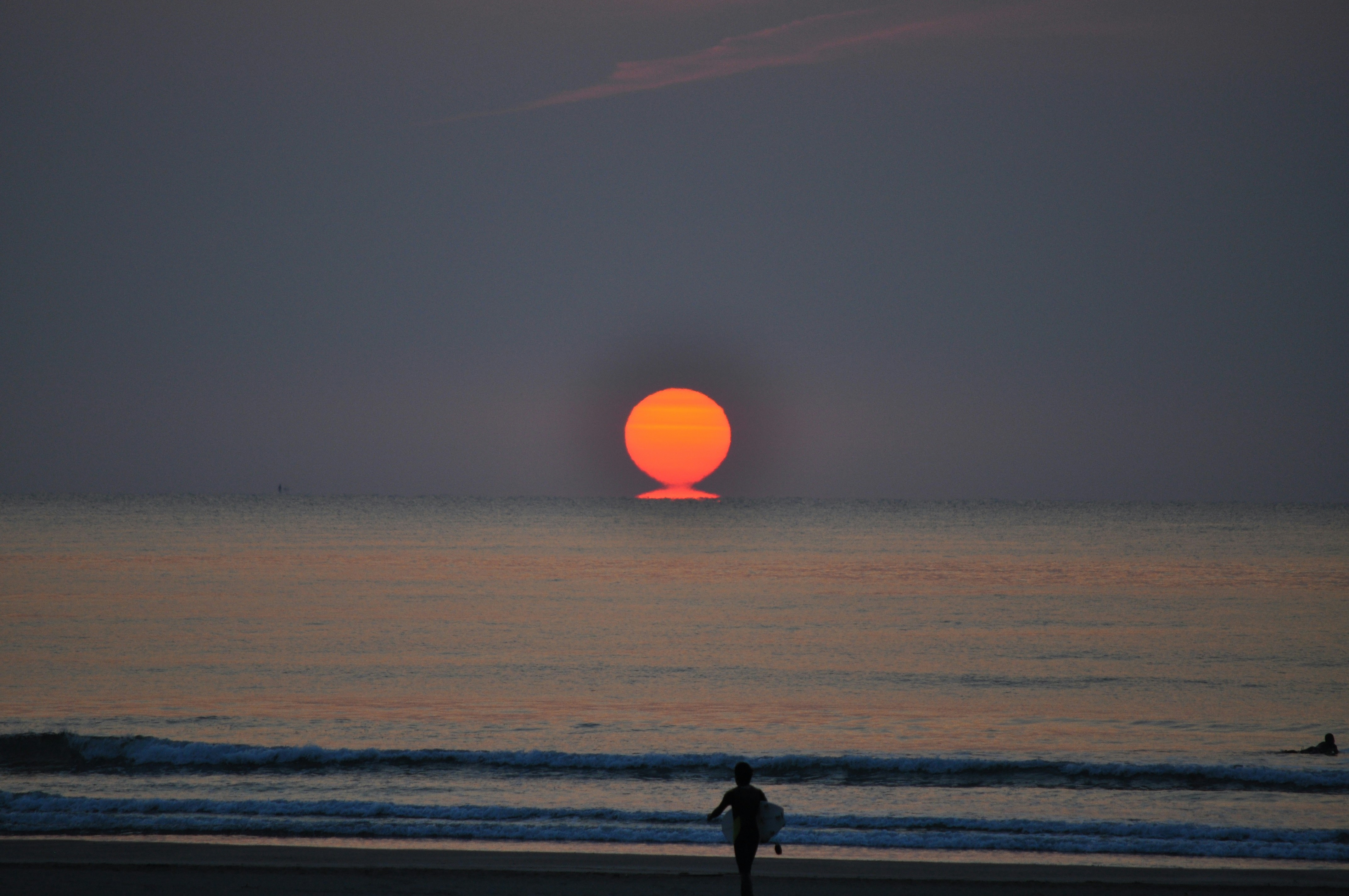夕暮れ時の浜辺を歩く男のシルエット