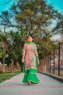 woman in green and white dress standing on gray concrete pathway during daytime