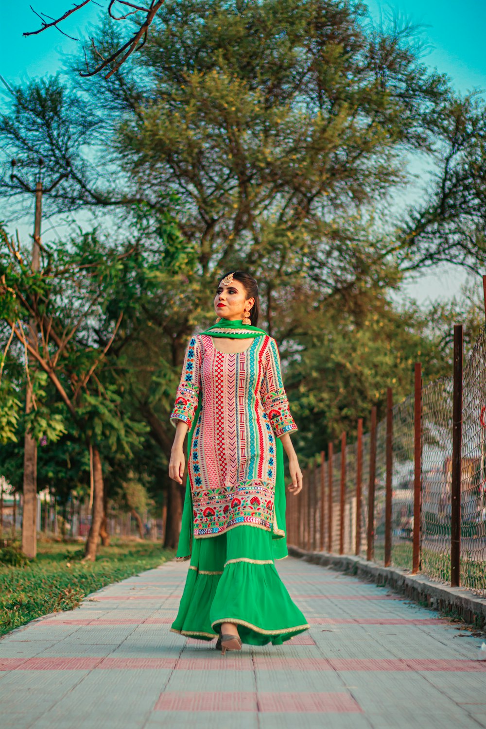 woman in green and white dress standing on gray concrete pathway during daytime