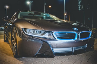 A sleek sports car glowing within a vibrant blue holographic display at night.