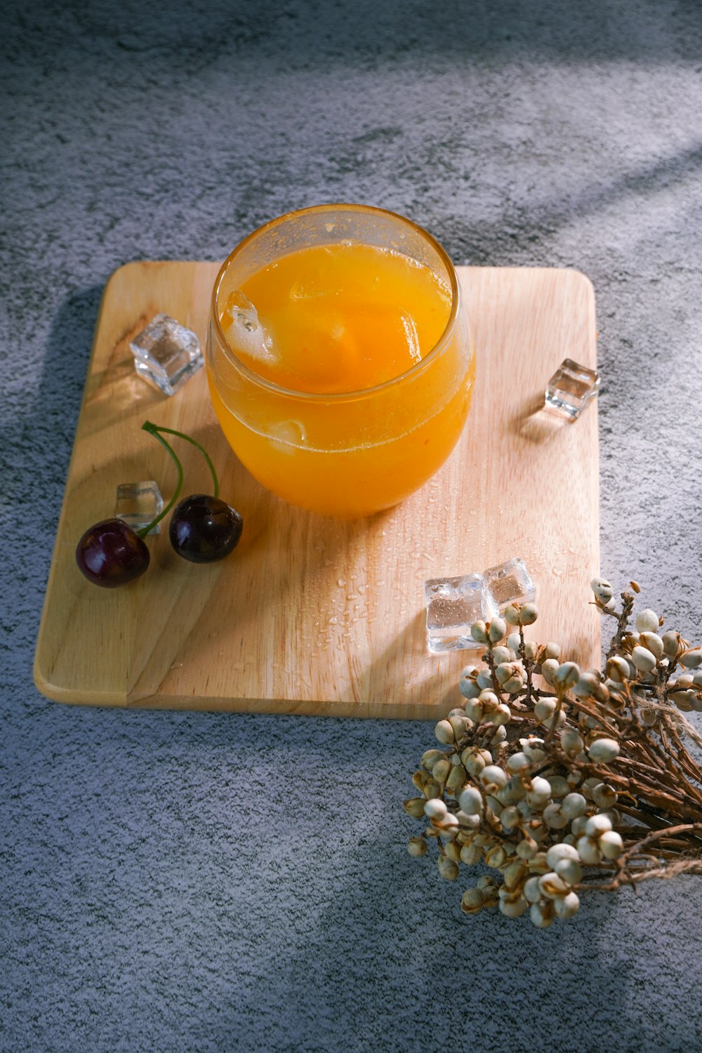 jugo de naranja en un vaso transparente sobre una tabla de cortar de madera marrón