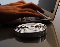 Hands typing on a laptop with symbolic patterns in the background.