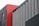 A modern architectural facade composed of geometric panels, primarily featuring a combination of red, gray, and black colors. The design features vertical lines and a mix of textures.