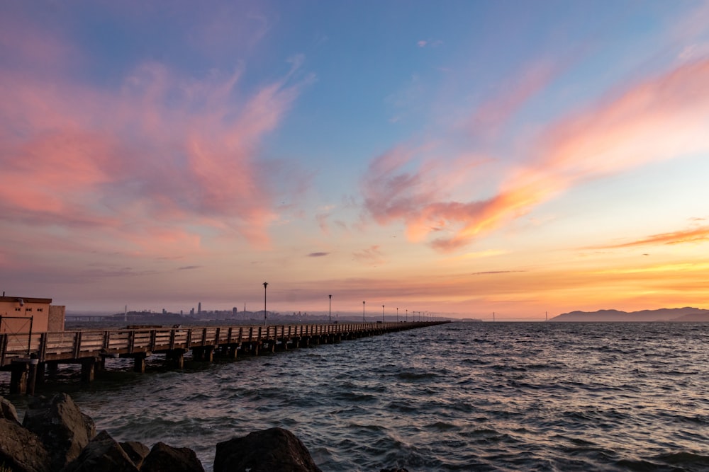 brown wooden dock on sea during sunset