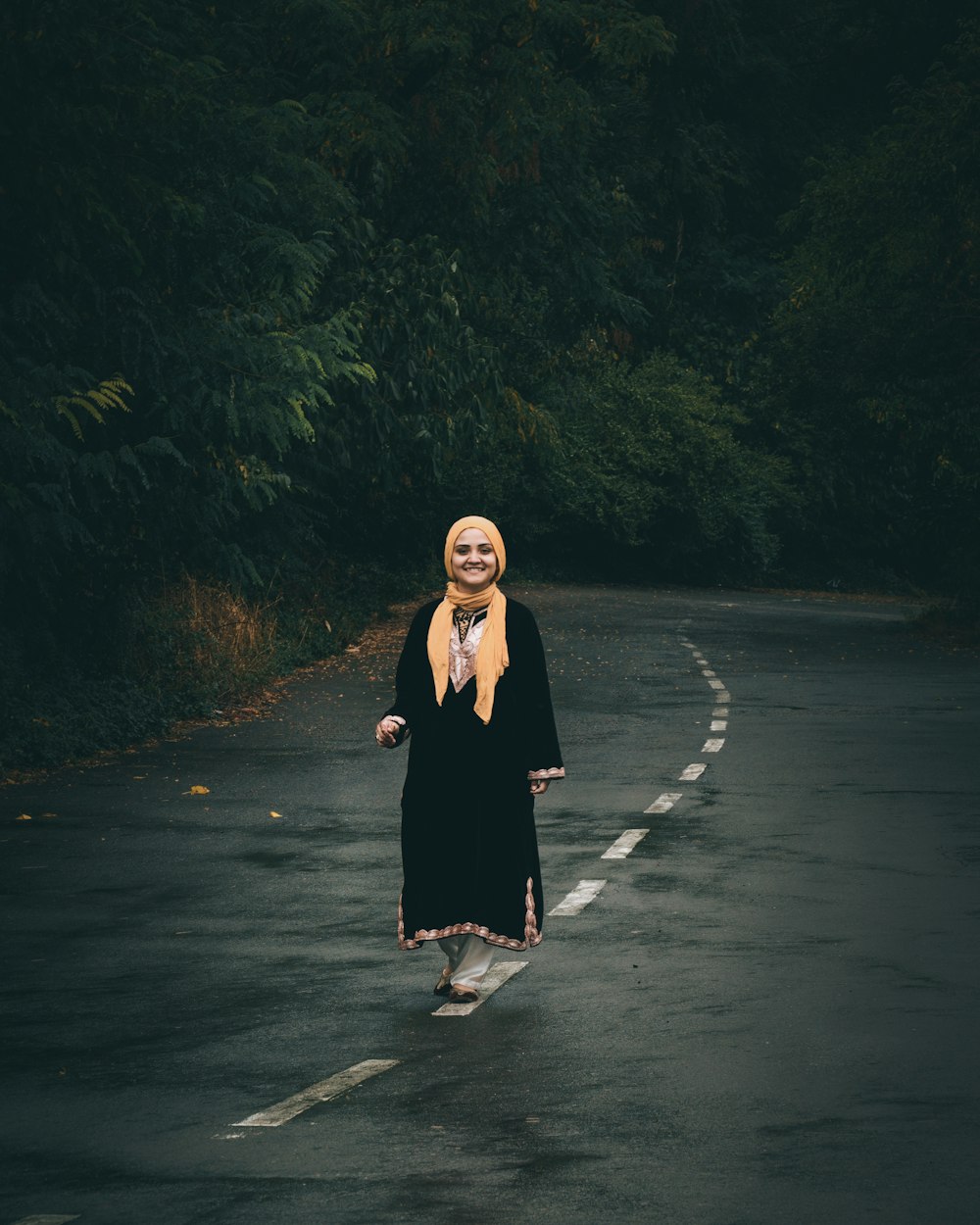 woman in black long sleeve dress standing on gray asphalt road during daytime