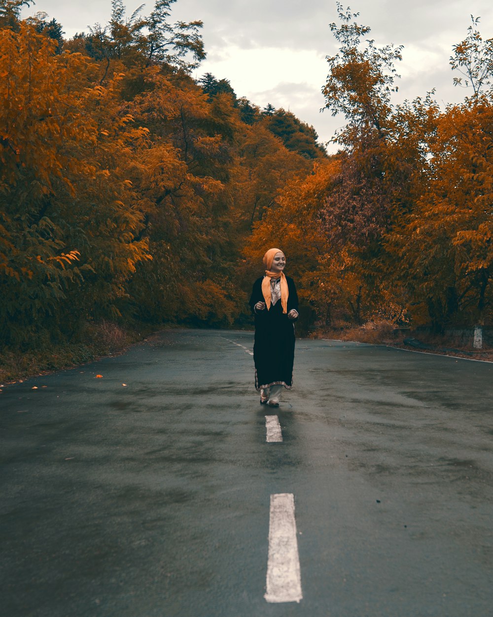 woman in black coat standing on road during daytime