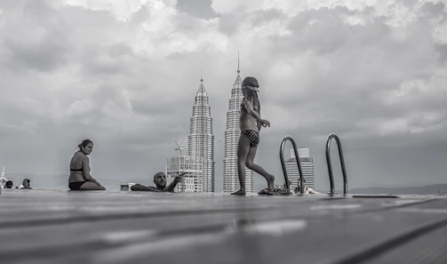 Group of friends smiling by a resort infinity pool, city skyline in the background.