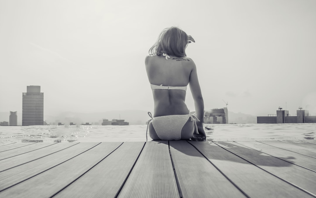 woman in black bikini bottom standing on wooden dock during daytime