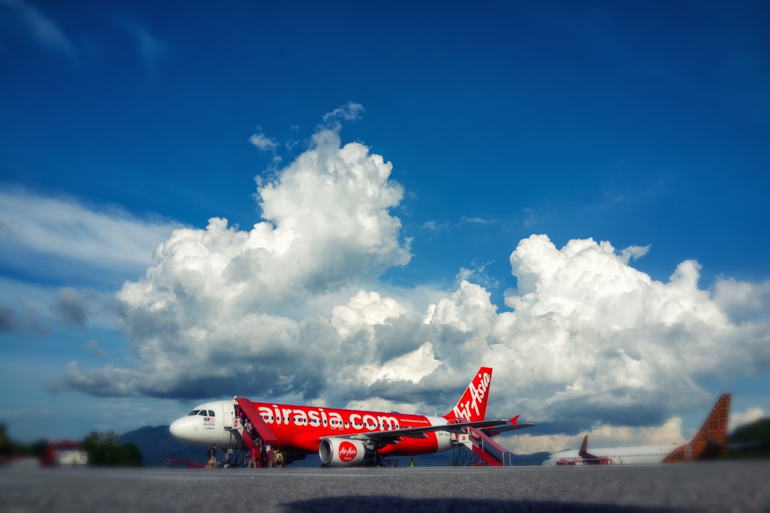 red and white passenger plane under blue sky and white clouds during daytime