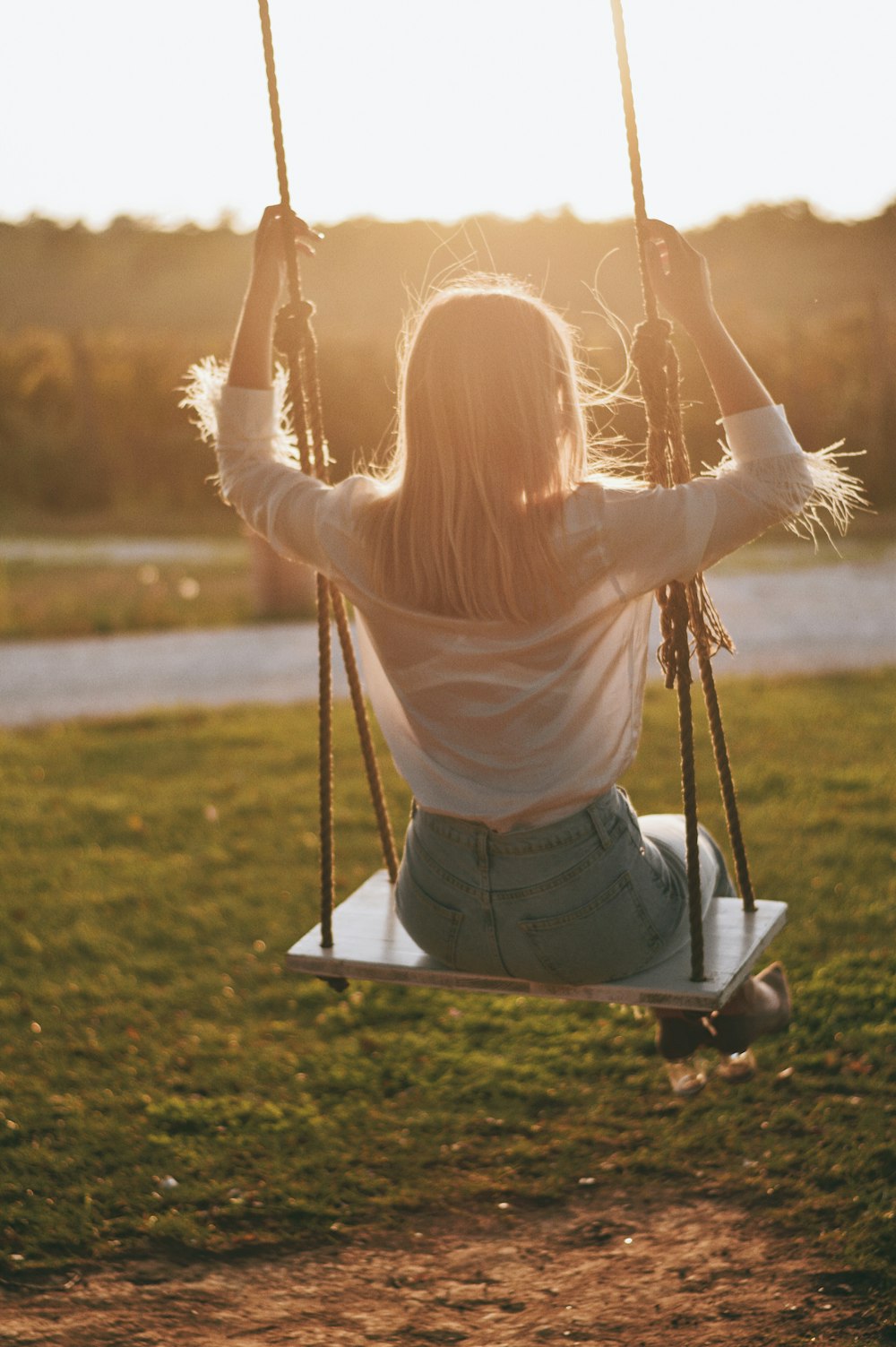 woman in white long sleeve shirt sitting on swing during daytime