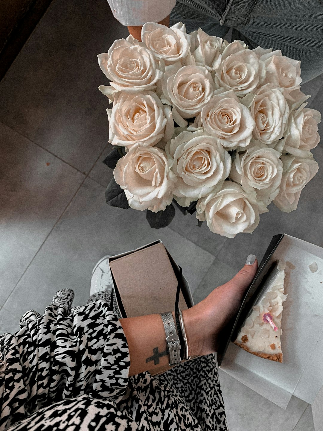 woman in black and brown peep toe heeled sandals standing beside white rose bouquet