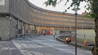 people sitting on concrete bench near brown concrete building during daytime