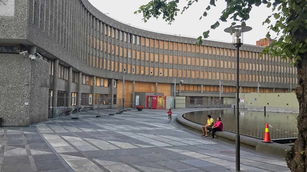 people sitting on concrete bench near brown concrete building during daytime