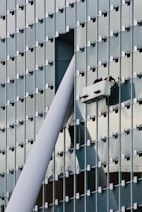 Image showing maintenance workers fixing a building’s exterior while a manager supervises.