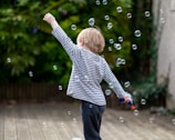 A candid moment of a toddler chasing bubbles with pure joy during a birthday party.