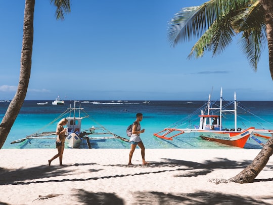 woman in pink bikini walking on beach during daytime in Boracay Philippines