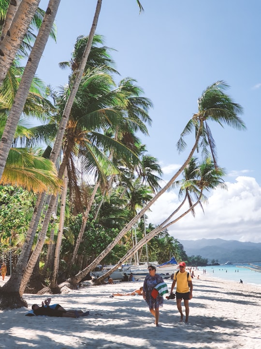 woman in red shirt sitting on beach during daytime in Boracay Philippines